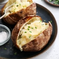 air fryer baked potatoes topped with butter and chives.