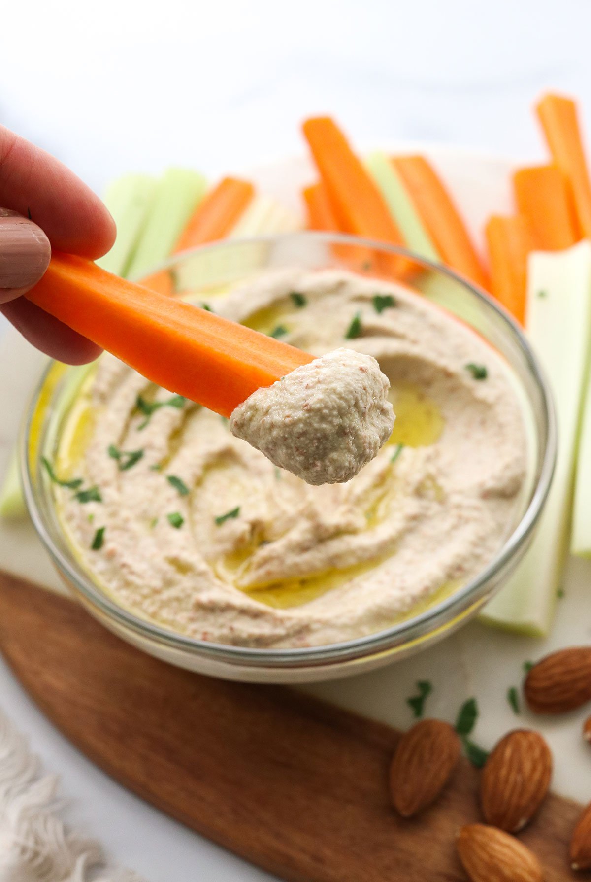 almond pulp hummus scooped on a carrot stick.
