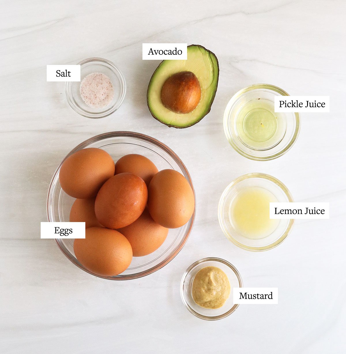 avocado deviled eggs ingredients labeled in glass bowls.
