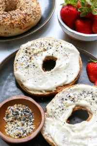 bagel topped with vegan cream cheese on black plate.