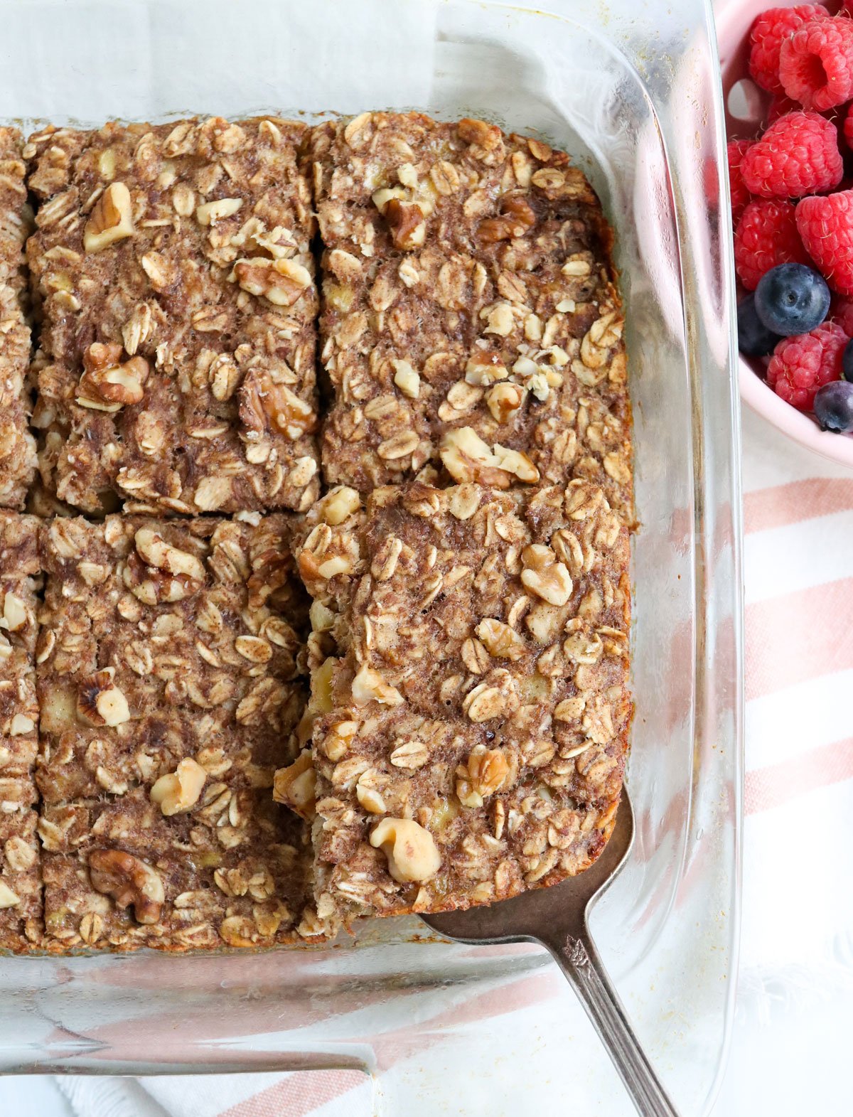 sliced oatmeal in baking dish with spatula.