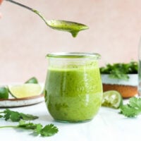 cilantro lime dressing lifted up on a spoon from a jar.