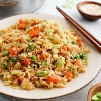 cauiflower fried rice served on plate with chopsticks.