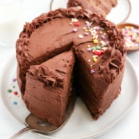 healthy birthday cake sliced with chocolate frosting on top.