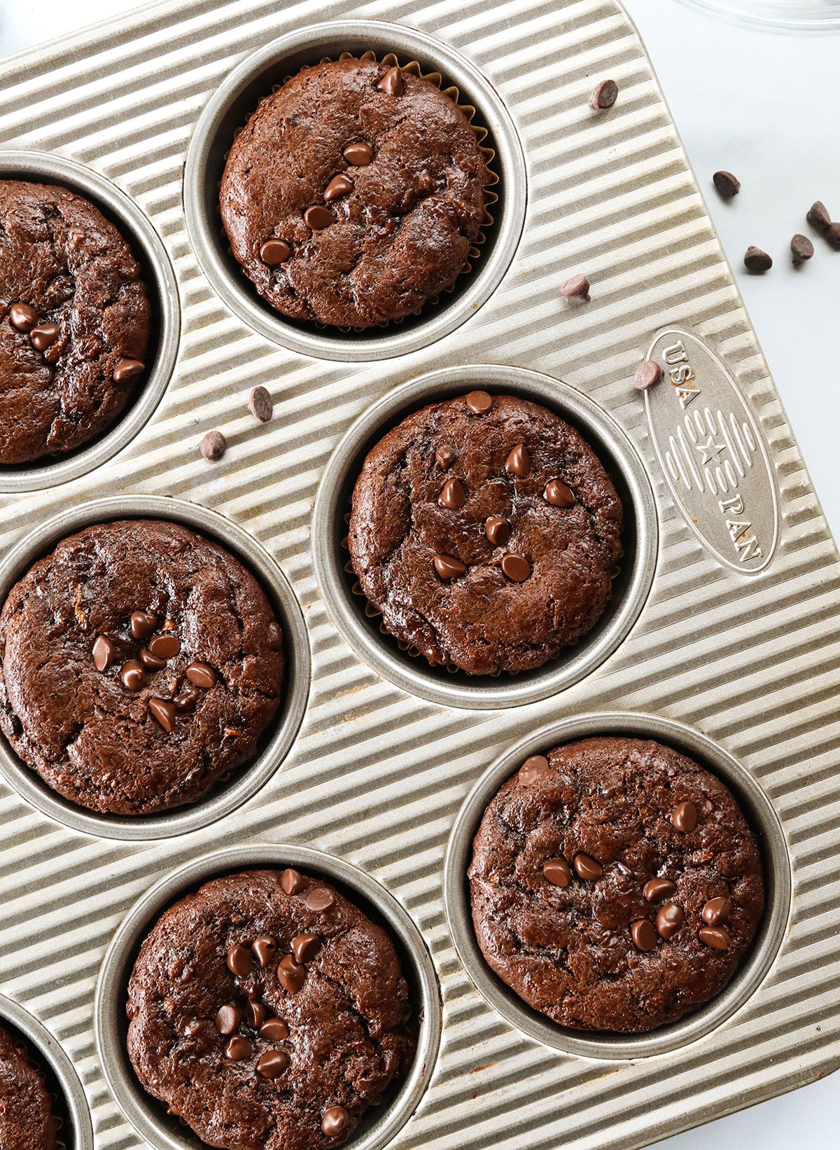 Chocolate zucchini muffins baked in a silver pan.