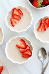 coconut panna cotta in bowls with strawberries on top.