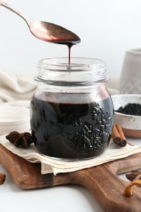 elderberry syrup pouring off of a spoon into jar