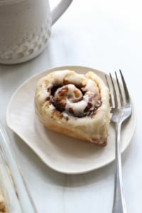 gluten free cinnamon roll served on white plate with fork.