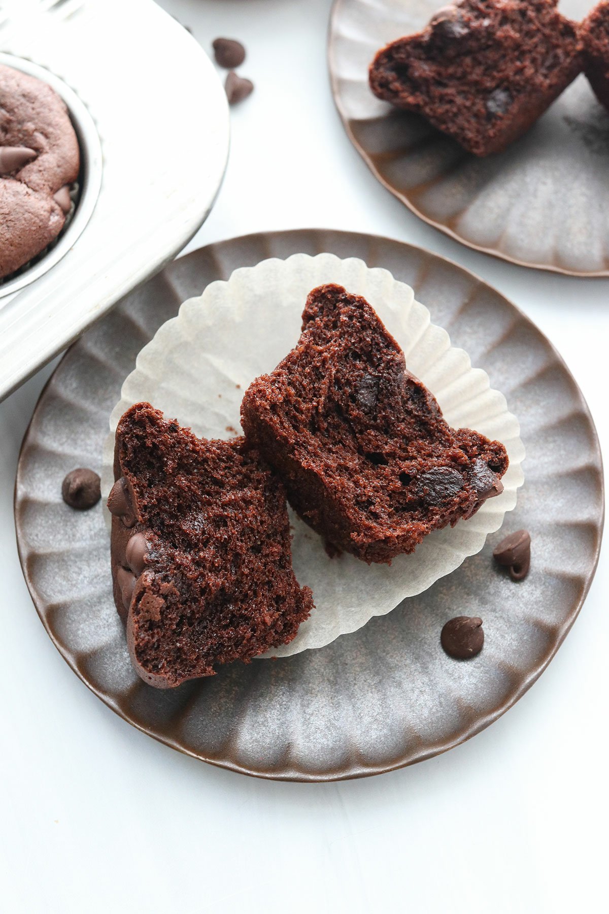 chocolate muffin split open on a plate to show the fluffy texture.