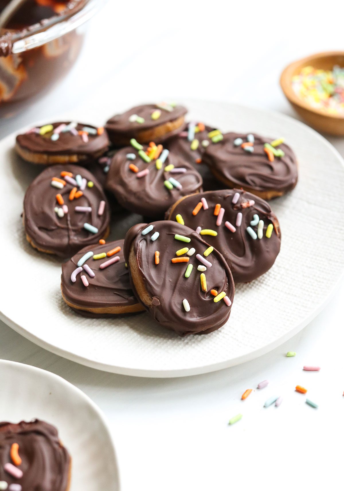 chocolate covered peanut butter eggs arranged on white plate with sprinkles.