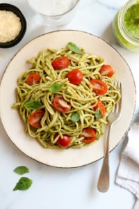 pesto pasta with tomatoes and fresh basil on plate