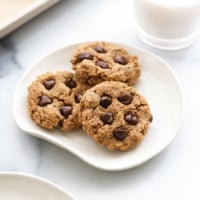 protein cookies arranged on a white plate with a glass of milk.