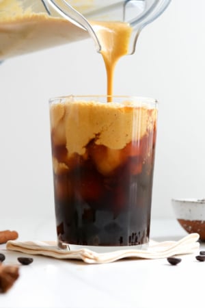 pumpkin creamer poured from a blender on top of iced coffee