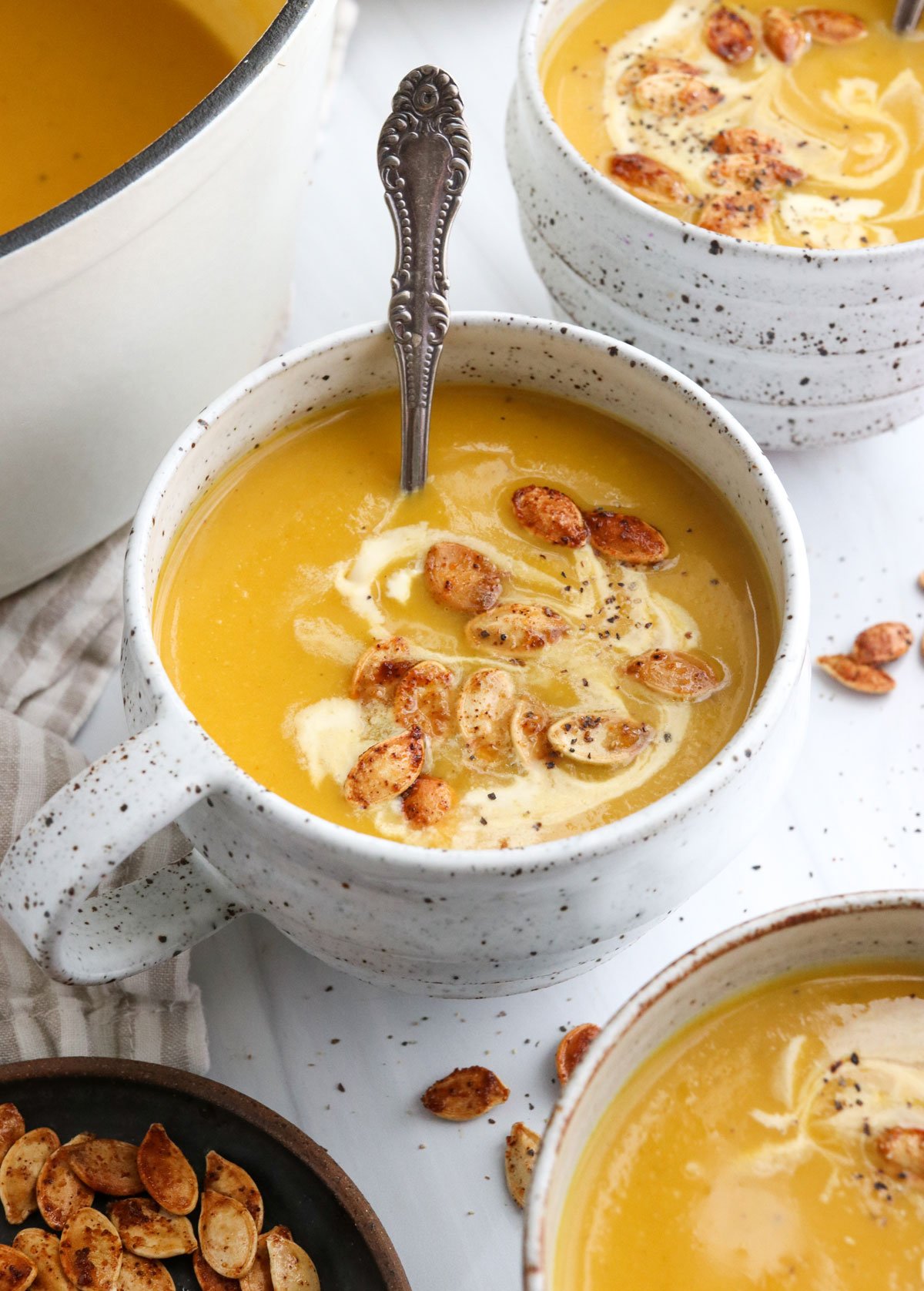 roasted pumpkin soup in a white mug with spoon