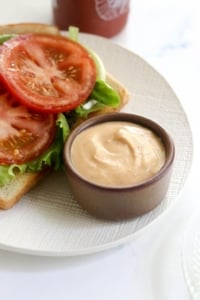 vegan sriracha mayo in a small brown bowl by a sandwich