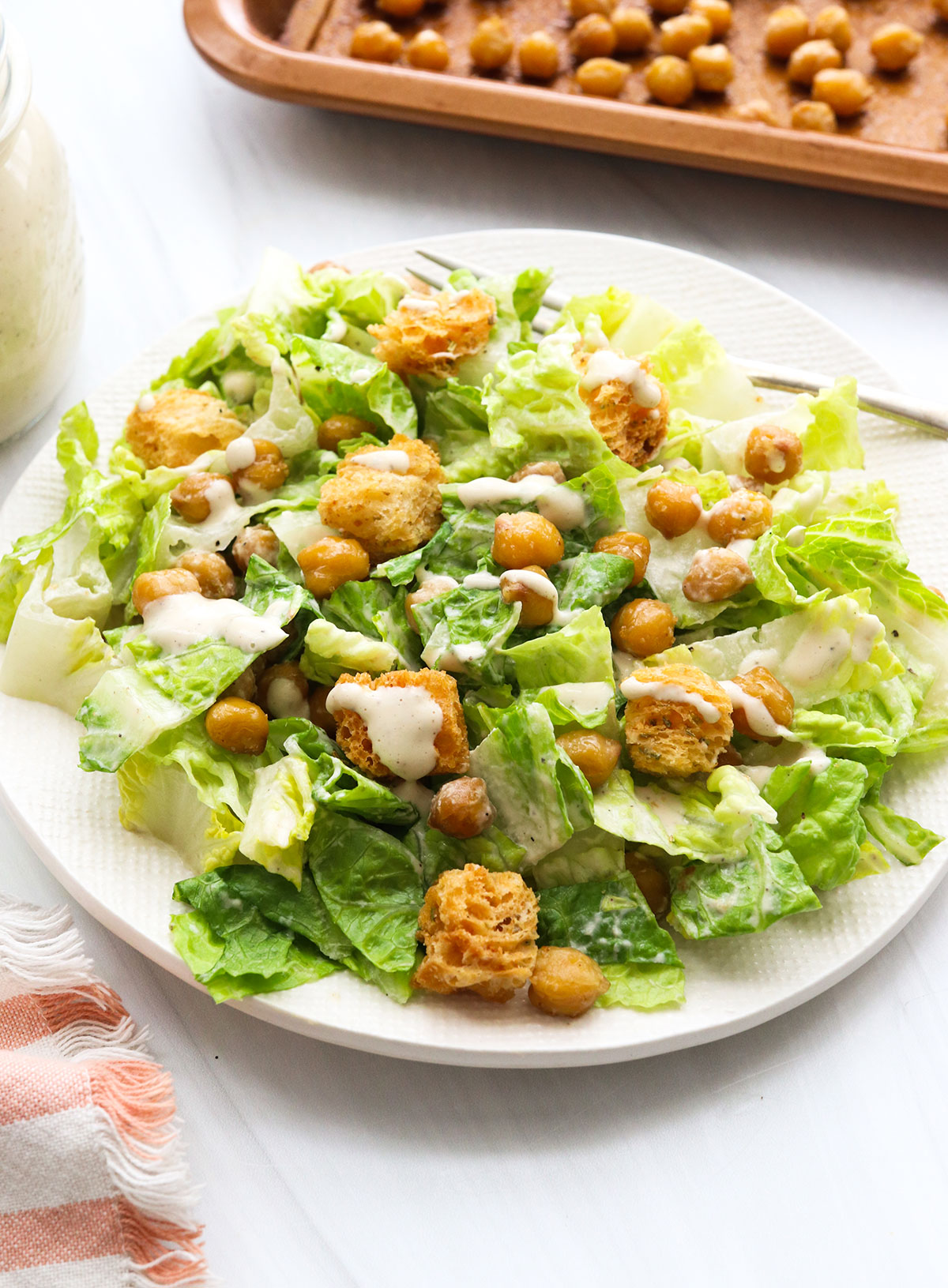 dressing and toppings added to caesar salad.