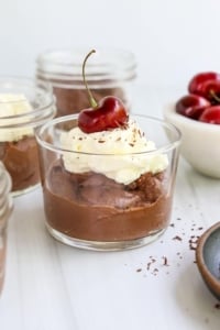 vegan chocolate mousse served with whipped cream and cherry.