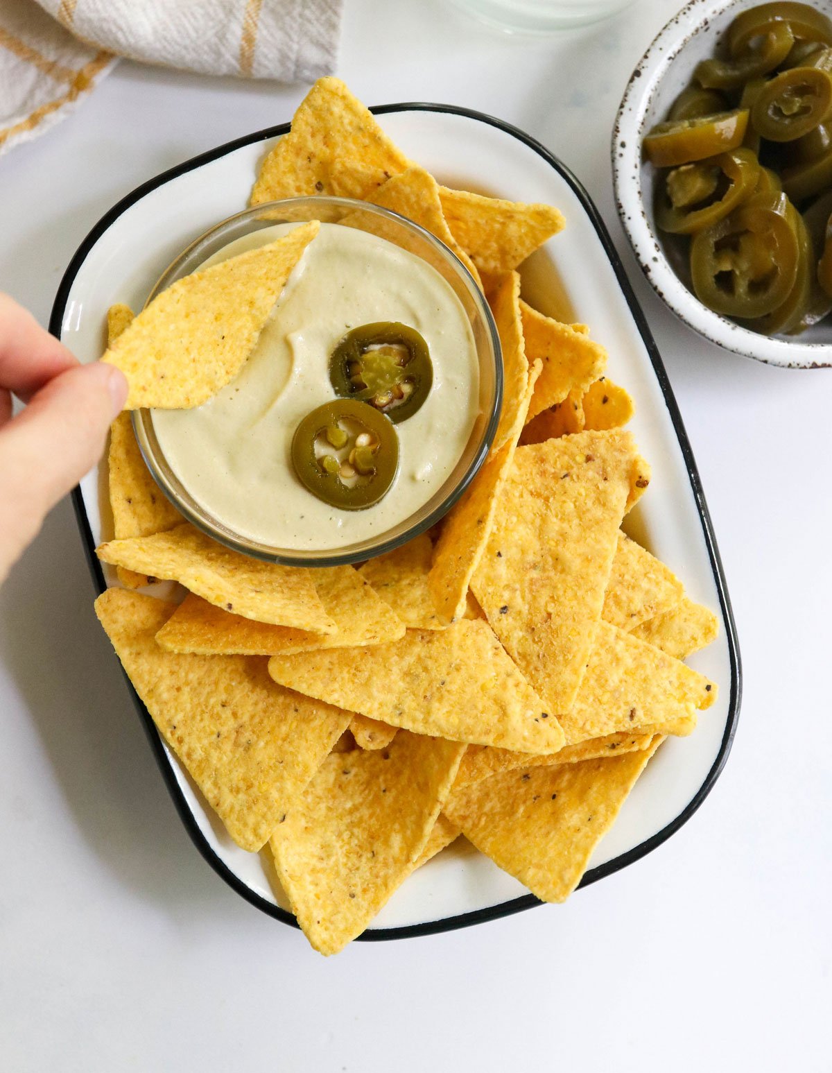 hand dipping chip into vegan nacho cheese