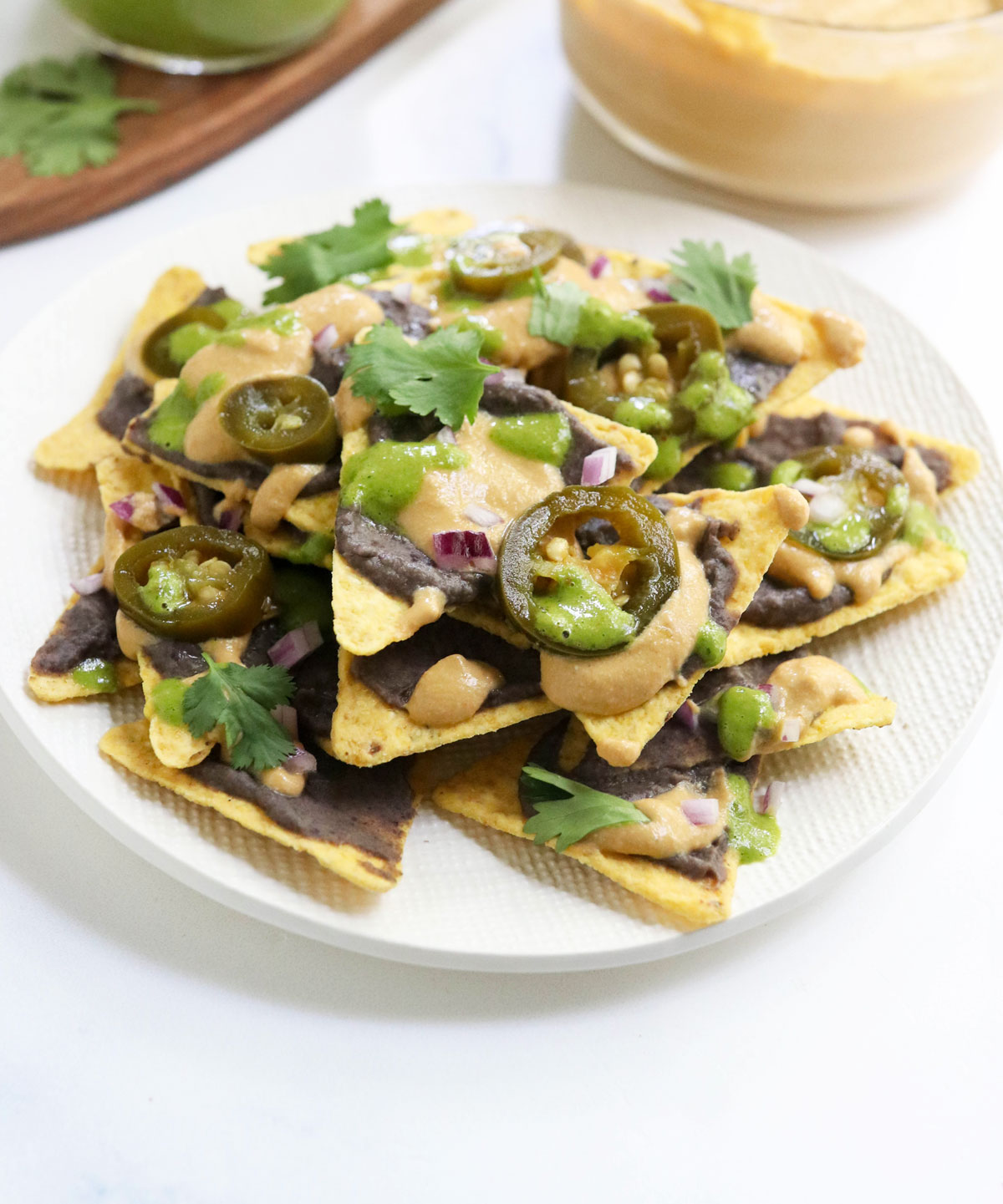 vegan nachos on a white plate with cilantro on top