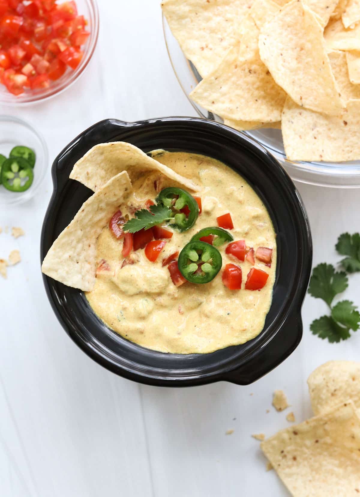 vegan queso with toppings and tortilla chips.